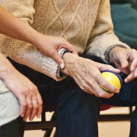 Woman helping an elderly man who is receiving rehabilitation therapy