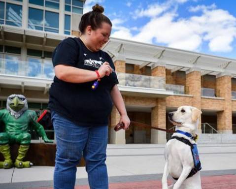 Female animal training working with a dog who's wearing a service animal vest
