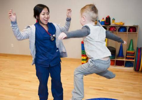 Child jumping on trampoline while working with therapist