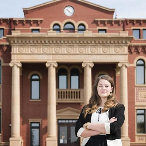 MPA graduate standing in front of city building