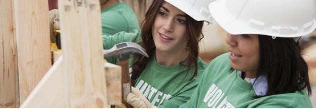 two volunteers building a house