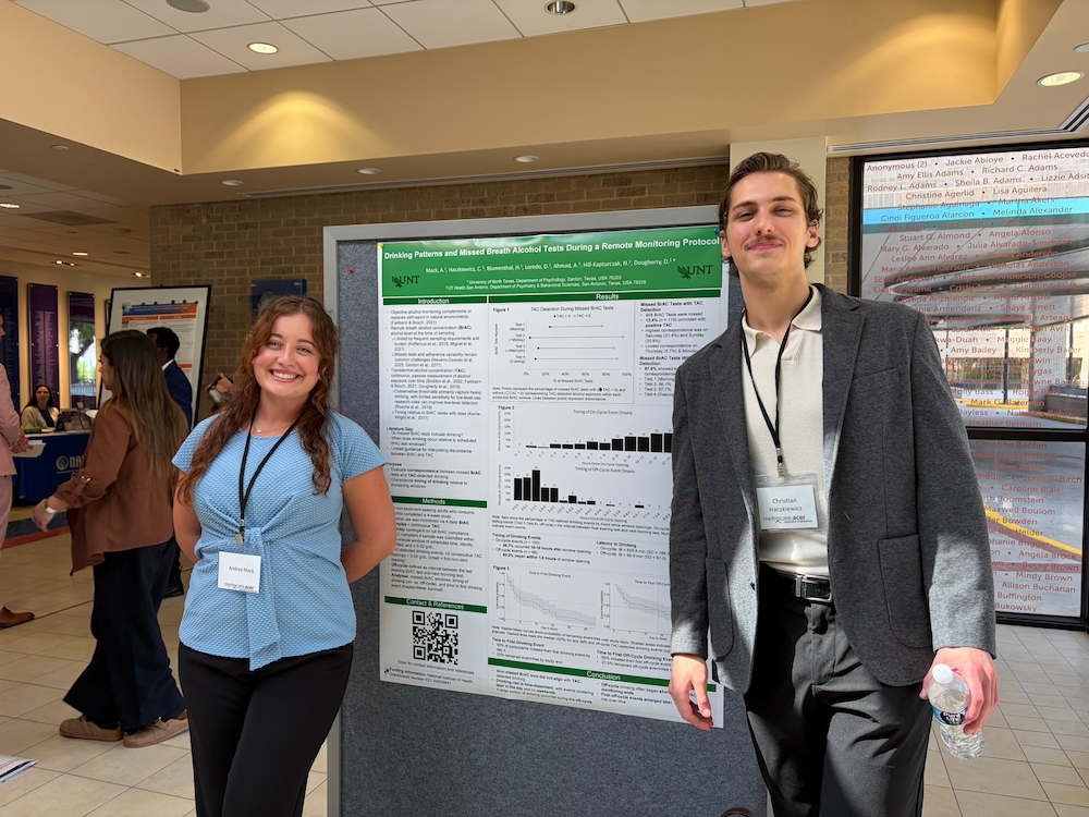 two researchers standing next to research poster