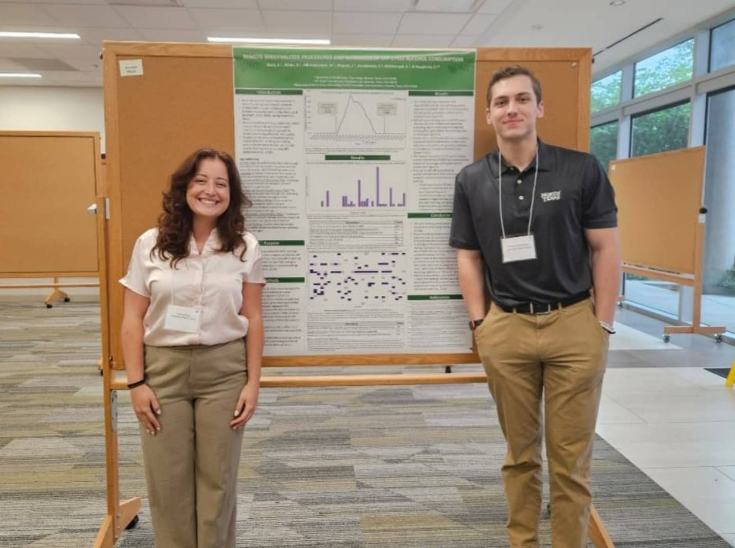 two researchers standing next to research poster