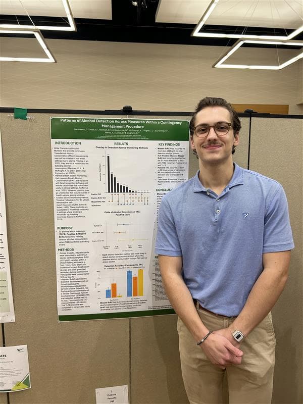 Researcher standing next to research poster