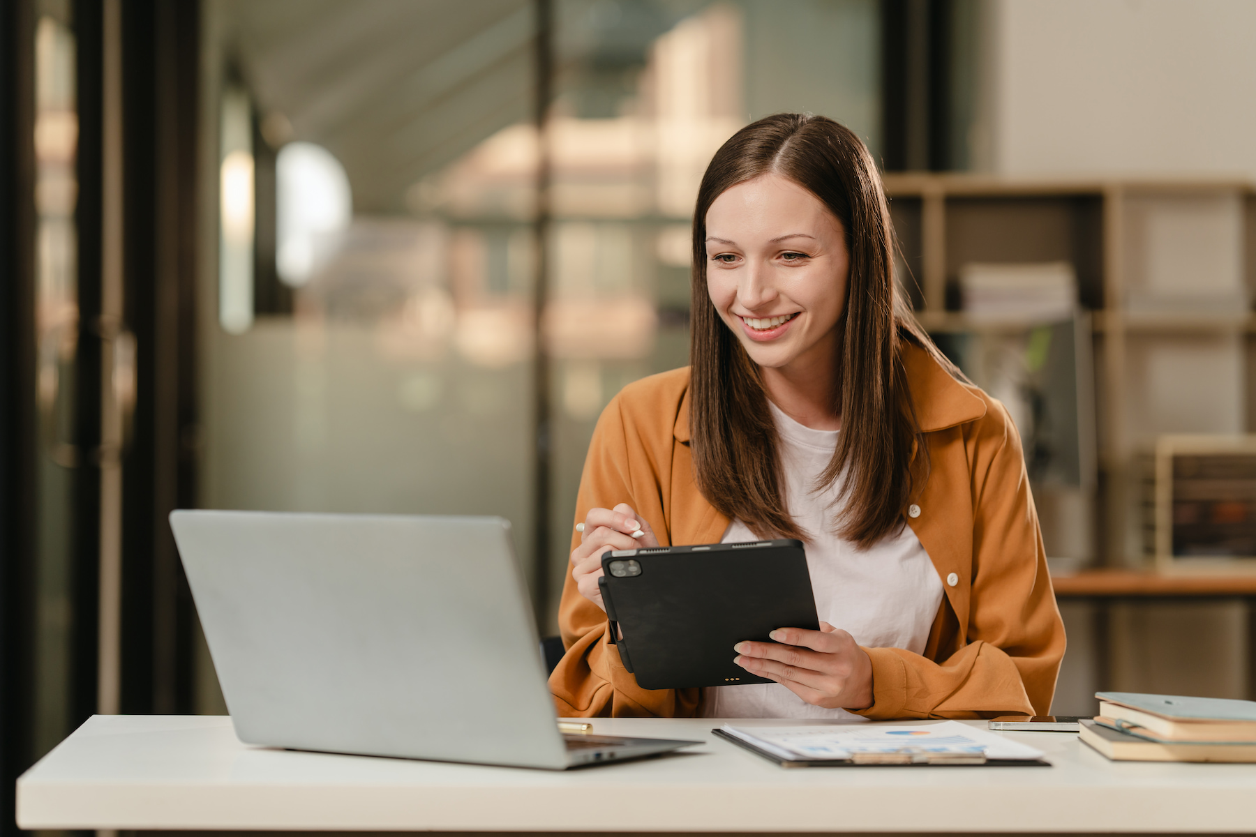 Person smiling at their computer with an ipad in their hand